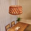 Walnut Geometric Wood Drum Pendant Light Above Wooden Dining Table with Rattan Chairs